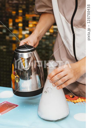 Kid Pouring Hot Water into Flask Creates Chemical Reaction 128788438