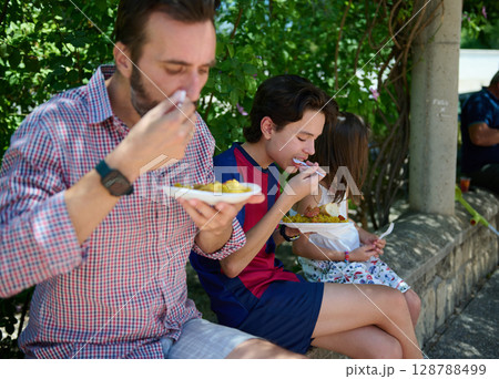 Family Enjoying Paella Together During a Spanish Village Celebration Outdoors 128788499