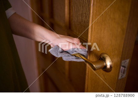 Carefully Hand Cleaning a Sparkling Glass Door with a Soft Sponge in the Kitchen Area 128788900