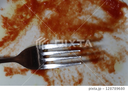 Empty dirty white plate with tomato sauce or ketchup on it. Empty dirty white plate with tomato sauce or ketchup on it. 128789680