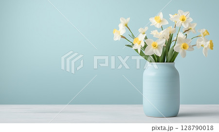 Elegant White Daffodils in Soft Blue Vase Against Minimalist Light Blue Background 128790018