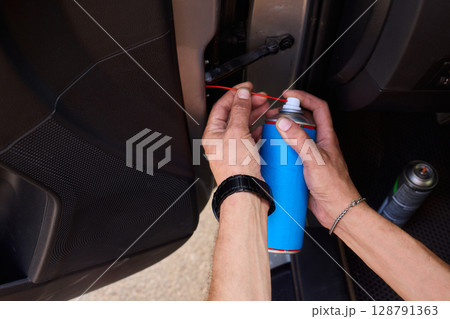 Applying spray lubricant to car door hinges helps keep them functioning smoothly Applying spray lubricant to car door hinges helps keep them functioning smoothly 128791363