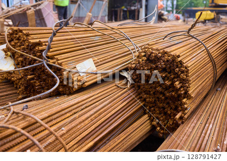 Stacked steel rods are prominently observed at a bustling construction site in progress Stacked steel rods are prominently observed at a bustling construction site in progress 128791427