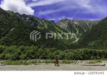上高地・小梨平から見た夏の穂高連峰の大パノラマ。椅子に座る人物が自然との一体感を表現。 128791441