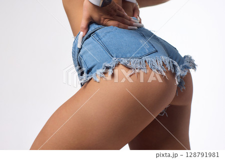 A Stylish and Fashionable Model Posing Confidently in Denim Shorts with Long, Flowing Blonde Hair 128791981
