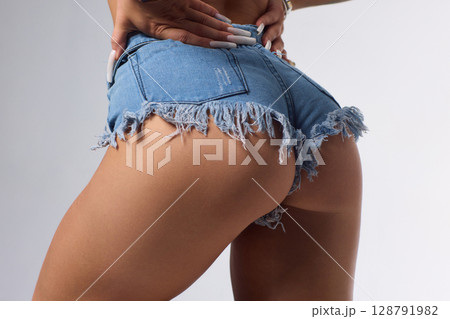 A Stylish and Fashionable Model Posing Confidently in Denim Shorts with Long, Flowing Blonde Hair A Stylish and Fashionable Model Posing Confidently in Denim Shorts with Long, Flowing Blonde Hair 128791982