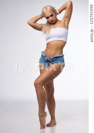 A Stylish and Fashionable Model Posing Confidently in Denim Shorts with Long, Flowing Blonde Hair A Stylish and Fashionable Model Posing Confidently in Denim Shorts with Long, Flowing Blonde Hair 128791999