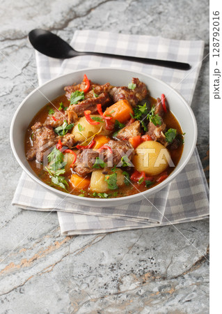 Beef stew Semur Daging with potatoes, carrot and a rich sweet-spiced soy sauce-based broth closeup in the bowl. Vertical 128792016