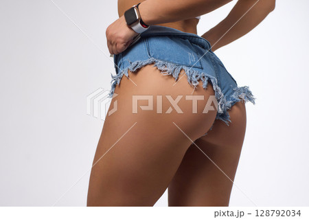 A Stylish and Fashionable Model Posing Confidently in Denim Shorts with Long, Flowing Blonde Hair 128792034