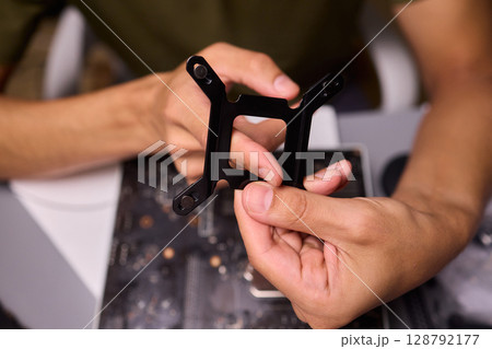 Hands Skillfully Assembling a Black Component for an Exciting Technology Project 128792177