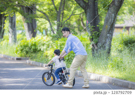 自転車に乗る練習をする親子　 128792709