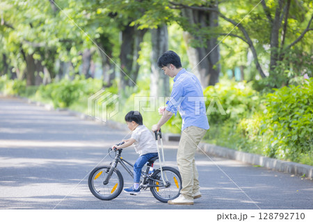 自転車に乗る練習をする親子　 128792710
