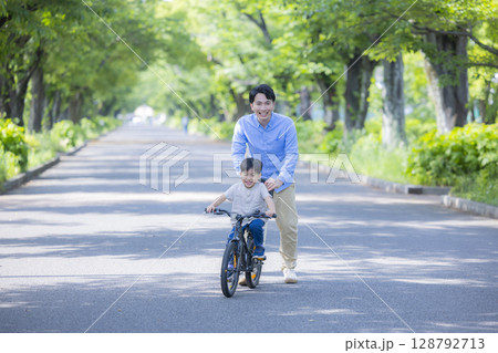 自転車に乗る練習をする親子　 128792713
