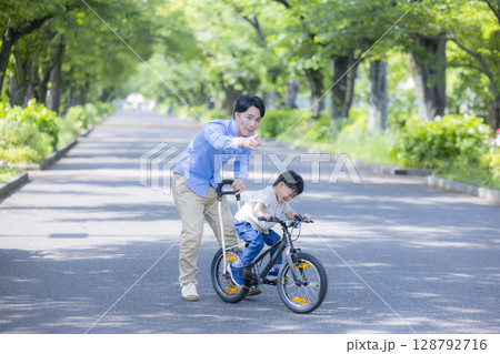 自転車に乗る練習をする親子　 128792716