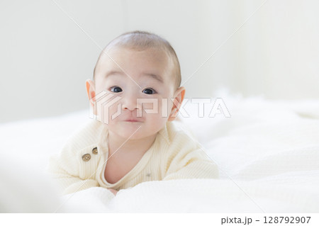 ベッドに寝転ぶ赤ちゃん　 128792907