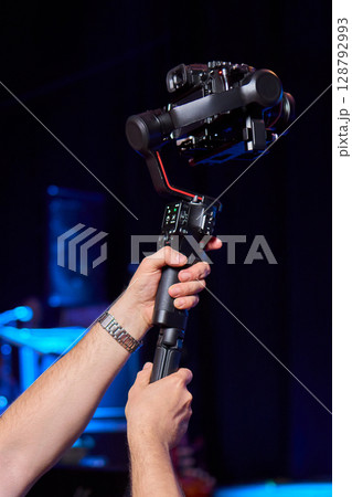 Closeup image showing someone gripping a DSLR camera with an articulated screen 128792993