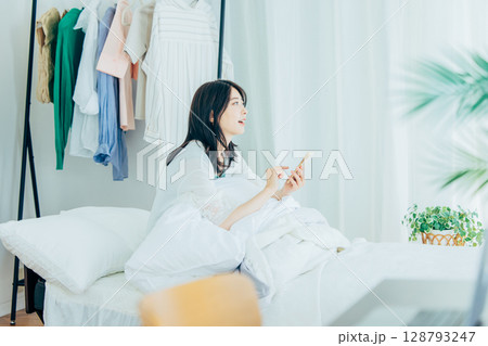ベッドでスマホを操作する若い女性 128793247