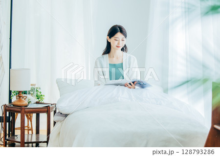 ベッドの上で雑誌を読む女性 128793286
