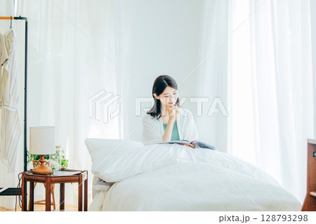 ベッドの上で雑誌を読む女性 128793298