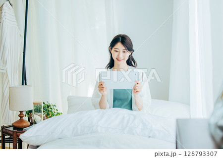 ベッドでタブレットを操作するミドルの女性 128793307