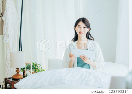 ベッドでタブレットを操作するミドルの女性 ベッドでタブレットを操作するミドルの女性 128793314