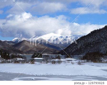 冬の裏磐梯、秋元湖。半凍結した湖面に雪の島、湖もの向こうには冠雪の箕輪山が青空に印象的で綺麗だ。 128793828
