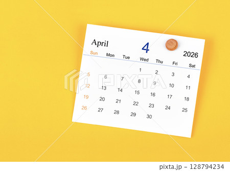 April 2026 card calendar and wooden push pin on yellow color wall. 128794234