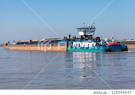 Rear view of a blue and white tugboat pushing a barge on Danube river, 128794837