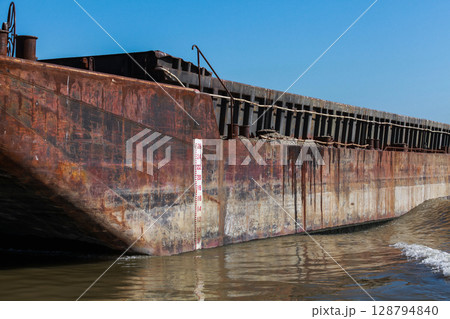 Rustic Metal Cargo Barge Floating on Calm Waters Under Clear Blue Sky 128794840