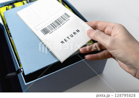 A woman's hand holds a return label over the blue box 128795828