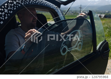Man Sitting in a Modern Compact Car on a Scenic Road 128795968