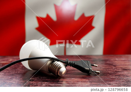 Electric cord and light bulb on the background of the Canadian flag, concept of the country's electricity supply Electric cord and light bulb on the background of the Canadian flag, concept of the country's electricity supply 128796658
