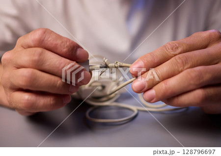 Carefully Repairing a Damaged Charging Cable with Skillful Hands for Best Results and Safety Carefully Repairing a Damaged Charging Cable with Skillful Hands for Best Results and Safety 128796697