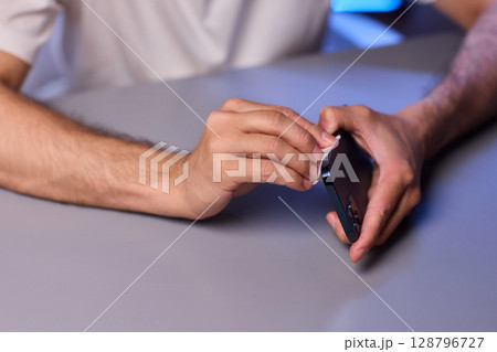 Cleaning a smartphone screen with a tissue needs attention for optimal hygiene and care 128796727