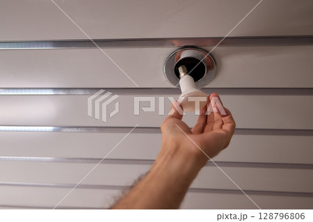 A Hand is Reaching for the Ceiling Fixture in the Interior Space of the Home or Room A Hand is Reaching for the Ceiling Fixture in the Interior Space of the Home or Room 128796806