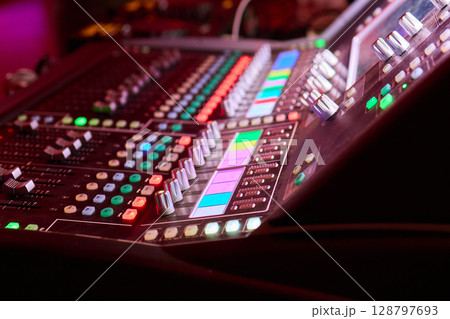 Closeup image of a hand mixing sounds on a control board, showcasing an audio technicians work 128797693