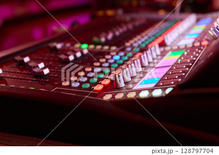 Closeup image of a hand mixing sounds on a control board, showcasing an audio technicians work Closeup image of a hand mixing sounds on a control board, showcasing an audio technicians work 128797704