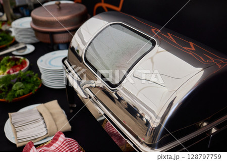 An Elegant Dining Setup Featuring a Silver Cloche and a Unique, Sophisticated Ambiance 128797759