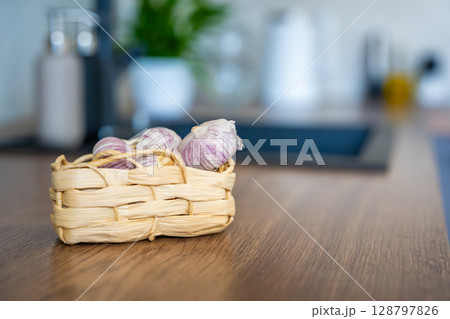 Basket with Chinese single clove garlic on kitchen countertop. Natural cooking ingredient, organic vegetable, and culinary preparation. Basket with Chinese single clove garlic on kitchen countertop. Natural cooking ingredient, organic vegetable, and culinary preparation. 128797826