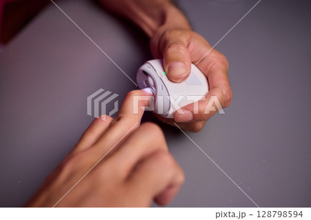 Close-up of an electric nail clipper in hand, modern personal care technology, highlighting compact design and functionality, modern gadget for personal grooming 128798594