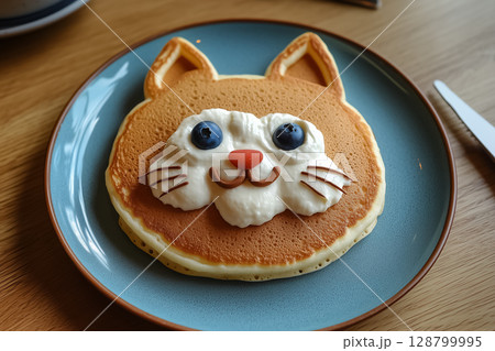 A plate of pancakes shaped like a cat with whipped cream whiskers and blueberry eyes 128799995