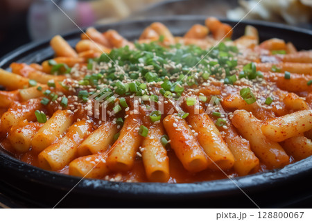 Spicy teokbokki with sliced onions, carrots, and sesame oil drizzle 128800067