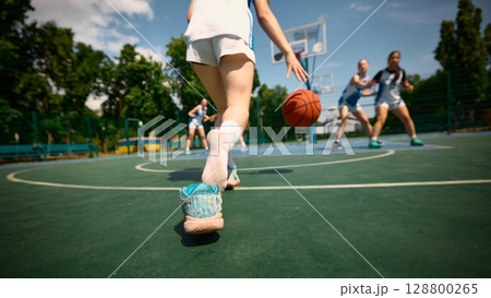 Women compete in basketball on outdoor court during a sunny summer day Women compete in basketball on outdoor court during a sunny summer day 128800265