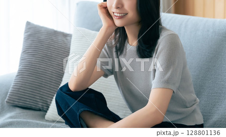 リビングのソファに座る笑顔の女性 リビングのソファに座る笑顔の女性 128801136