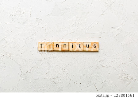 TINNITUS word written on wood block. TINNITUS text on cement table for your desing, concept 128801561