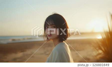 夕暮れの海岸を歩く女性 128801649