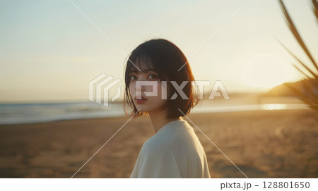 夕暮れの海岸でポーズをとる女性 128801650