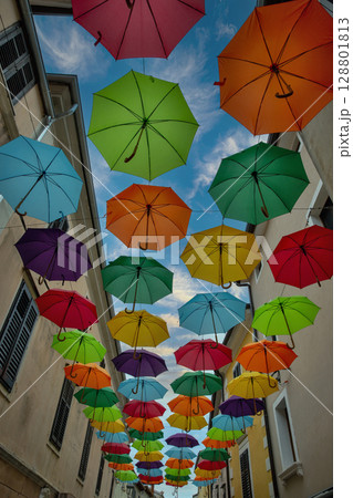 Vibrant umbrella canopy installation in narrow European alley. Vibrant umbrella canopy installation in narrow European alley. 128801813