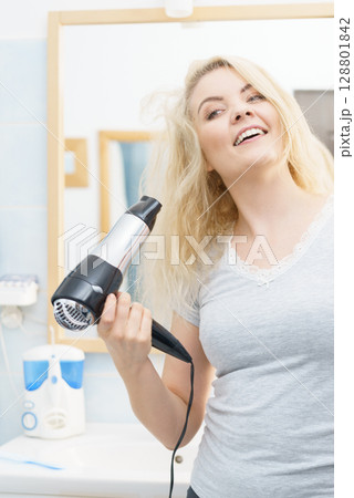 Blonde woman using hair dryer Blonde woman using hair dryer 128801842