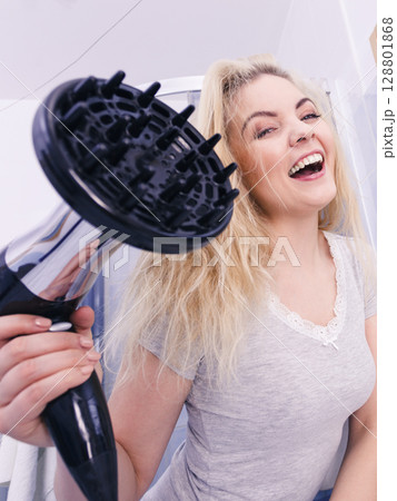 Woman doing curls with hairdryer diffuser 128801868
